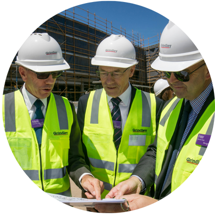 Warrigal executives and CEO wear high vis and hard hats at building site