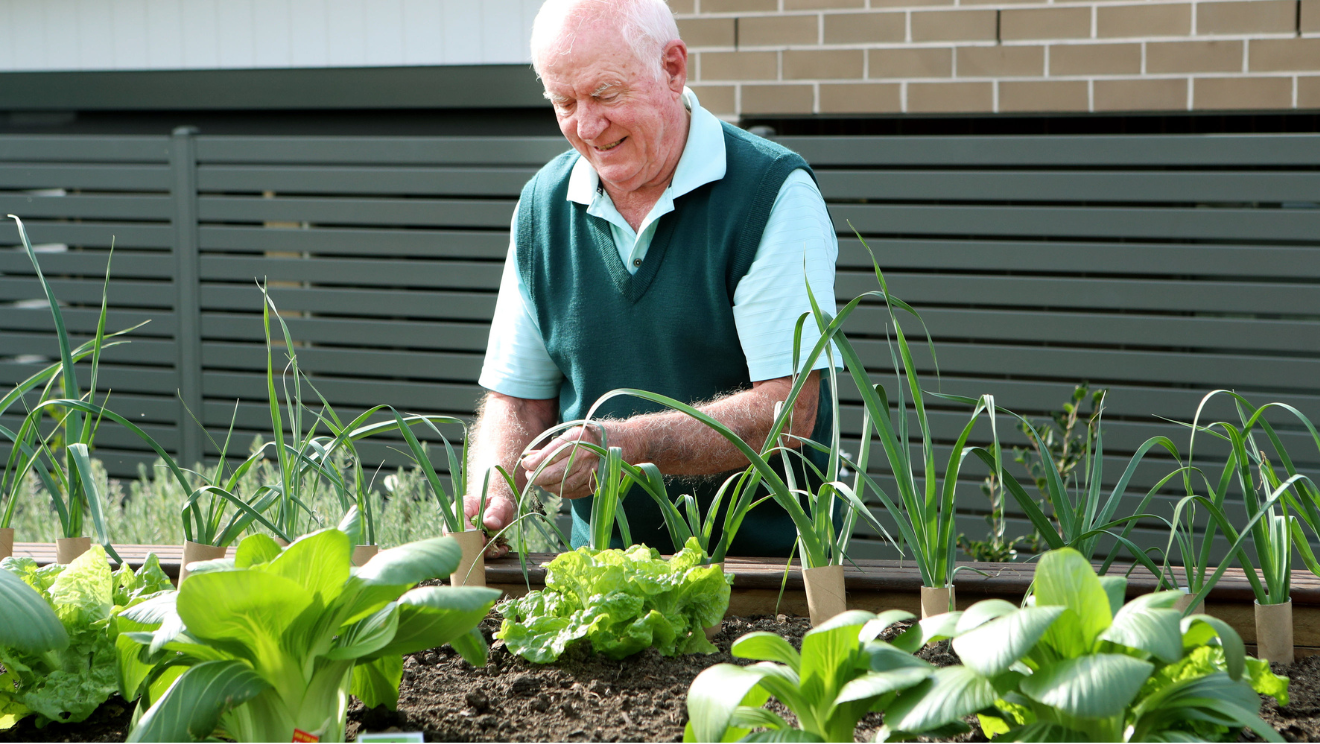Warrigal village resident smiling while gardening on a sunny day