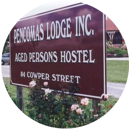 Pencomas Lodge Inc sign with white writing on a brown background in a bed of flowers