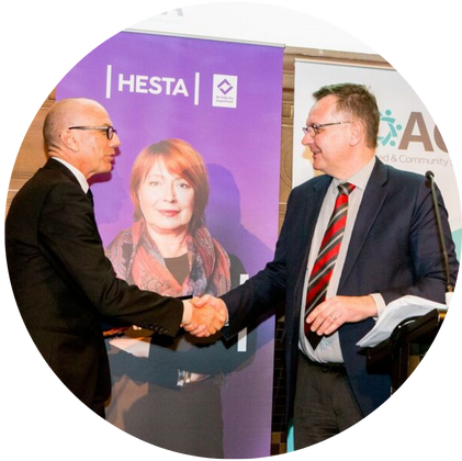 Former Warrigal CEO Mark Sewell shakes hand at HESTA award ceremony