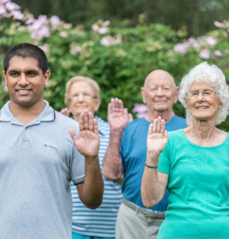Warrigal staff member enjoys exercise with aged care residents outside in the sunshine smiling.
