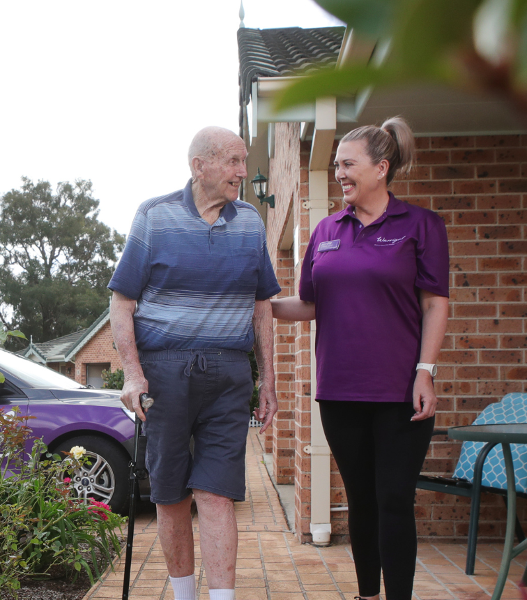 Warrigal staff member smiling while walking alongside older man