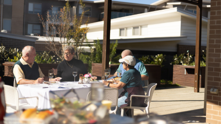 A group of Warrigal Shell Cove villagers meet together in the barbeque area.