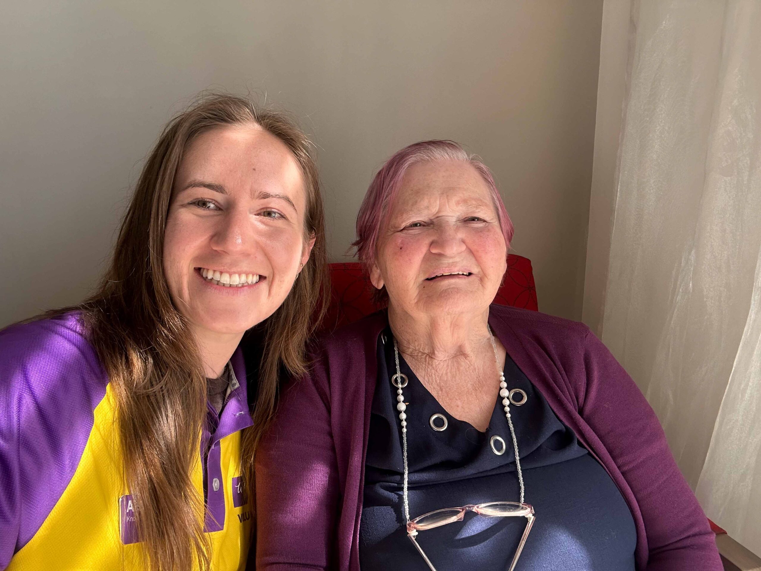 Jeune bénévole souriant à côté d'un résident souriant